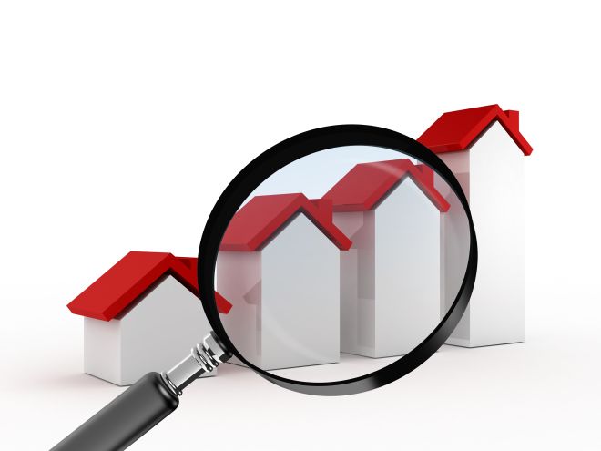 Magnifying glass focusing on real estate, graph bars of houses with red roof, searching or analyzing sales of houses, isolated on white background.